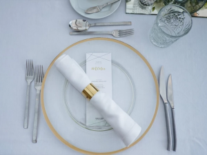 Table setting with gold-rimmed plate, menu, and cutlery