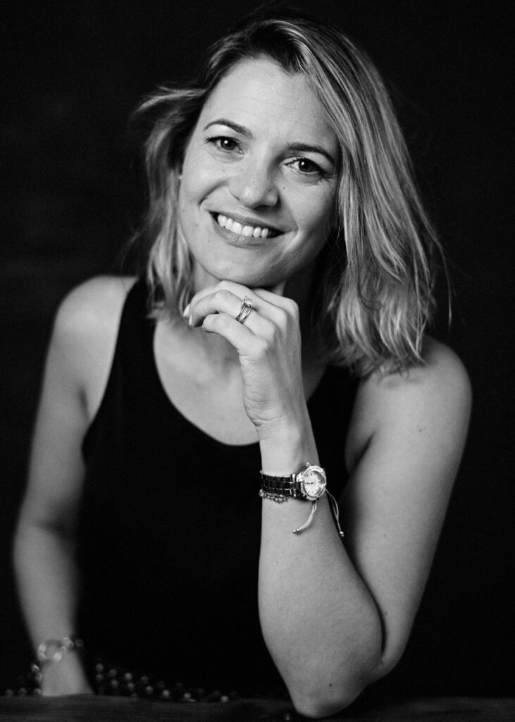 Smiling woman with hand on chin, wearing a watch and ring