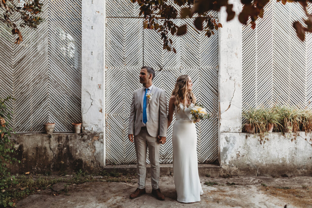 Couple holding hands, standing in front of a patterned wall.