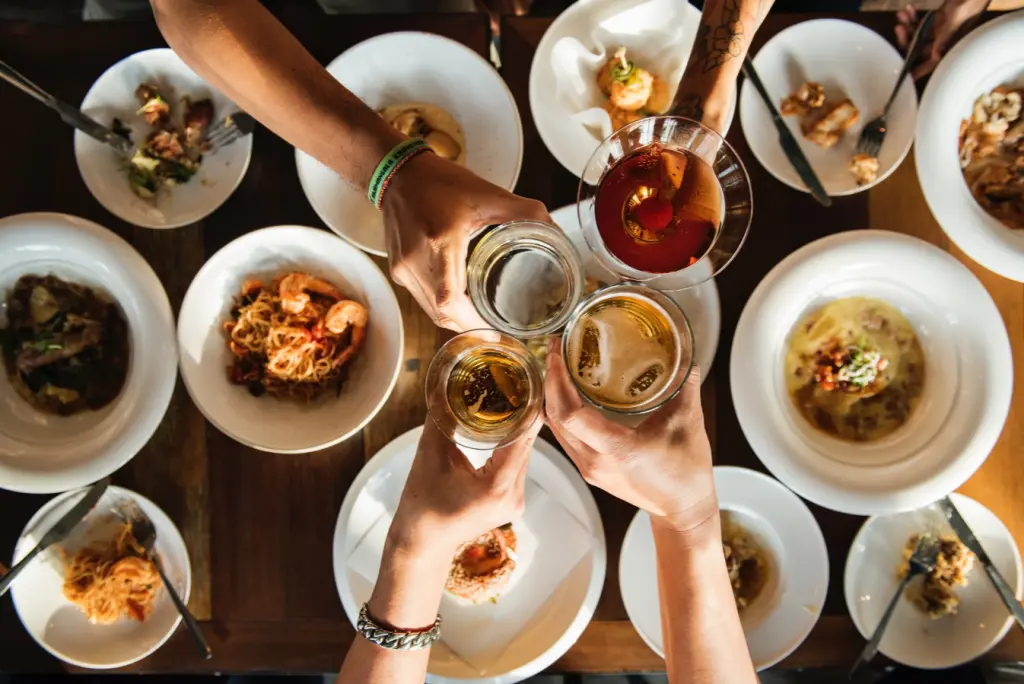 People toasting drinks over a table full of food