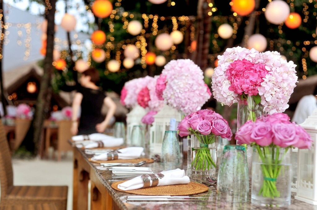 Wedding table with pink flowers, place settings, string l...