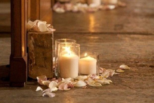 Candles in glass holders with rose petals on the floor