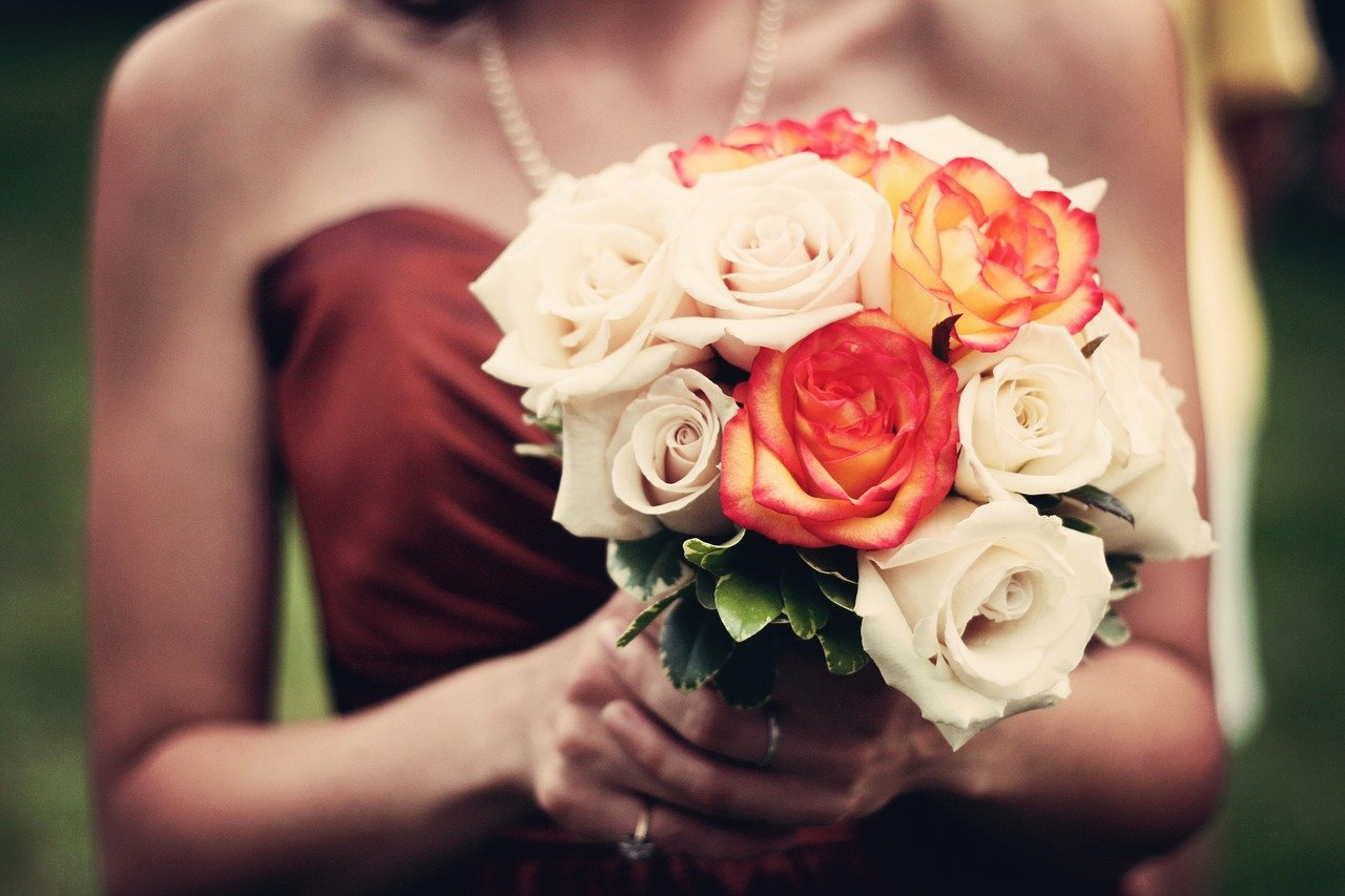 Woman in strapless dress holding white and orange roses.