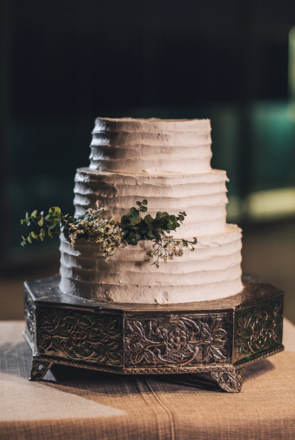 Three-tiered white wedding cake with green foliage