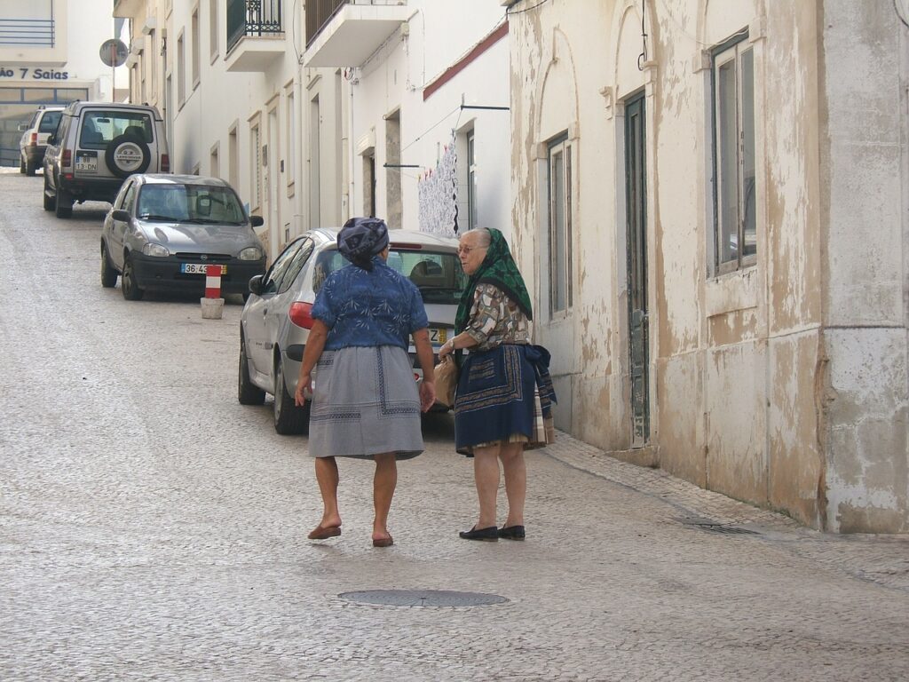 Two women in traditional clothing on a cobblestone street.