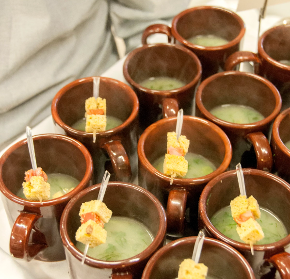 Brown mugs of soup with crouton and meat skewers