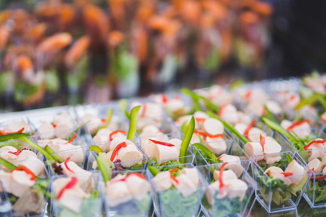 Small appetizers in clear cups, with meat, lettuce, peppers.