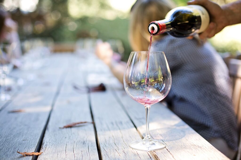 Red wine pouring into a glass on a wooden table