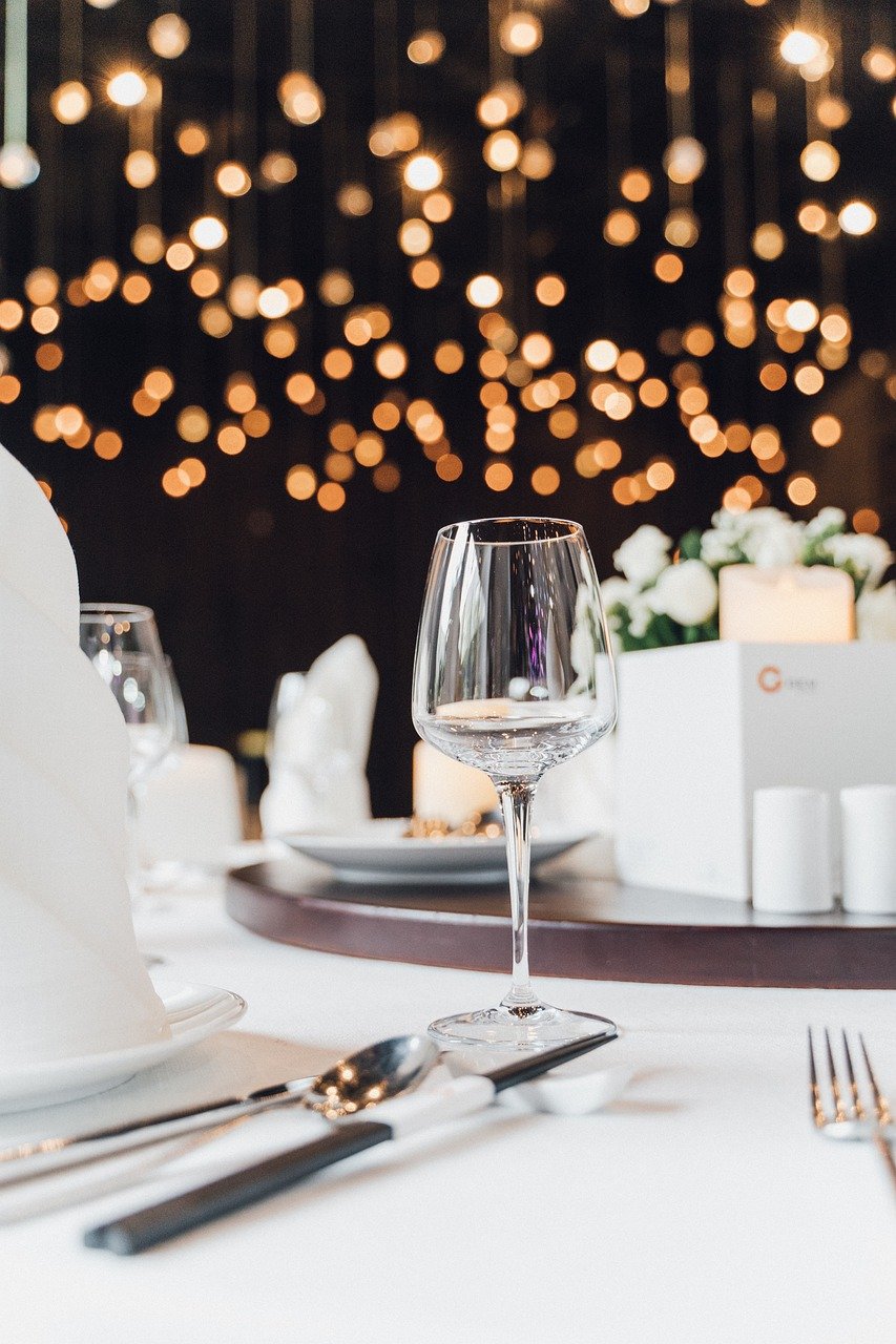Elegant table setting with wine glass, cutlery, bokeh lights