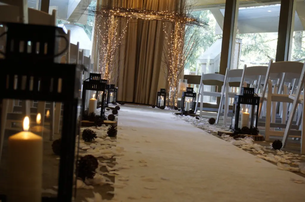 Wedding aisle with lanterns, pinecones, and white petals.