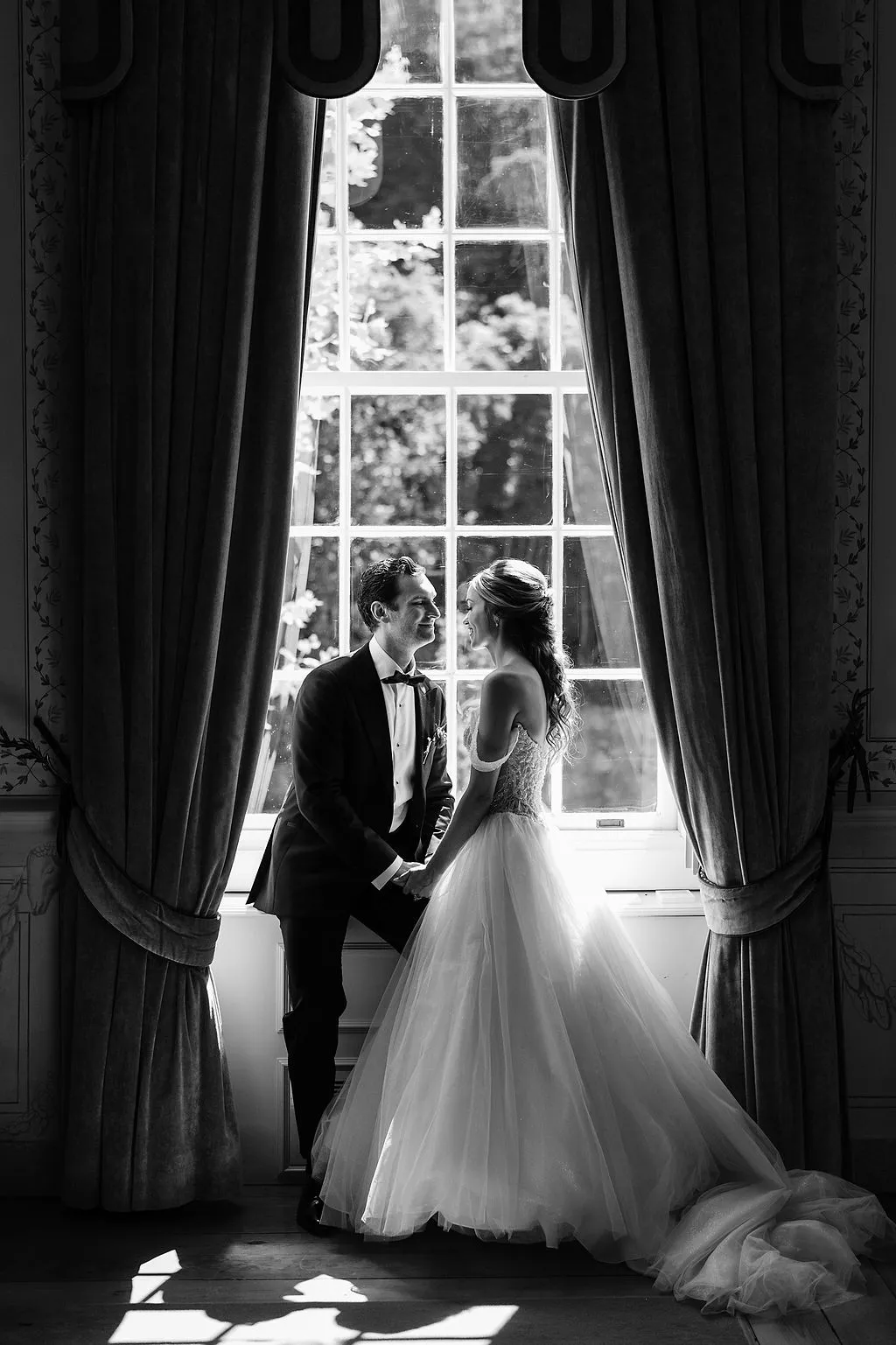 Bride and groom holding hands, looking at each other