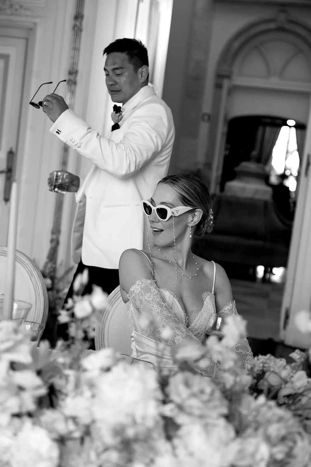 Man in white tuxedo, woman in lace dress, white sunglasses