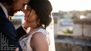 Groom embracing bride, foreheads touching, eyes closed